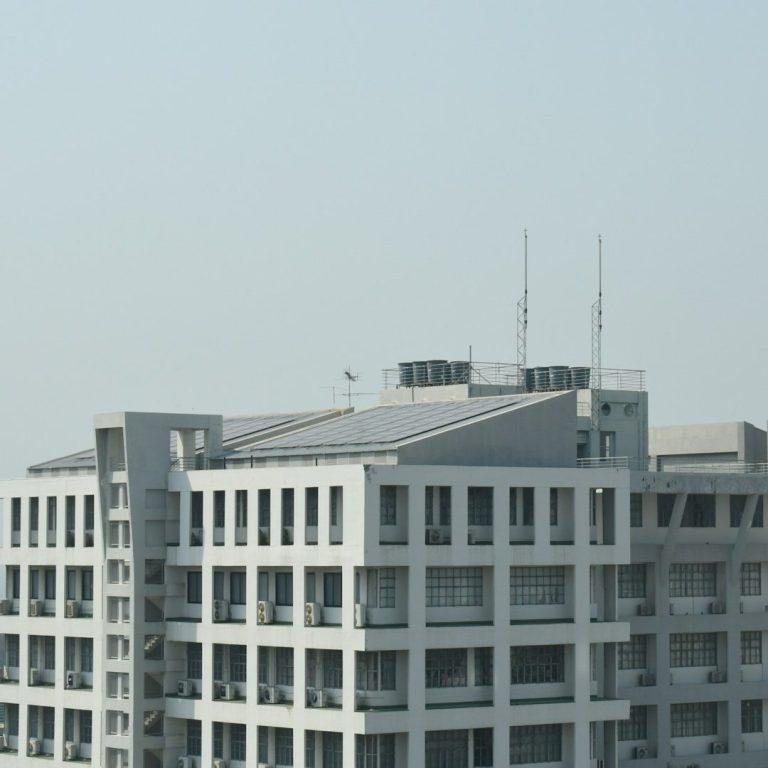 Graues Bürogebäude mit Solarpanelen und Antennen auf dem Dach.