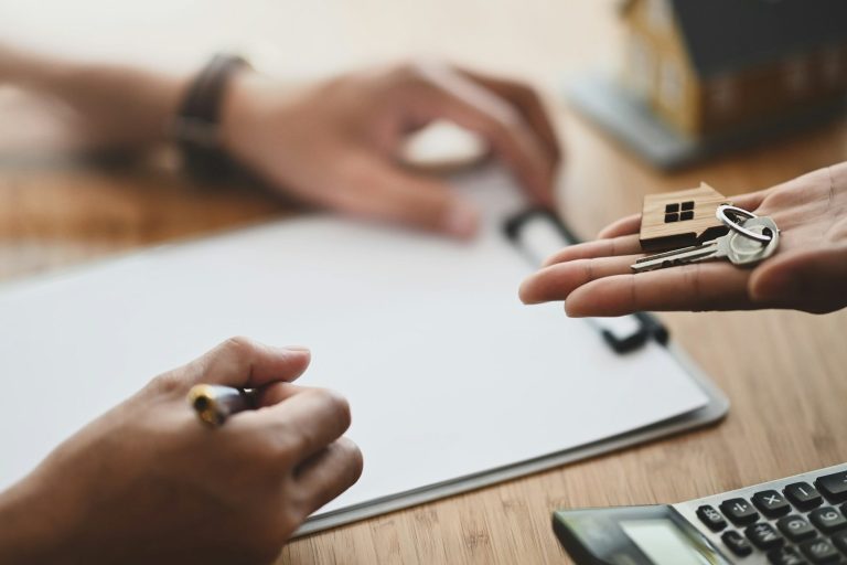 SE-Verwaltung Schlüsselübergabe mit Notizblock und Taschenrechner auf dem Tisch.